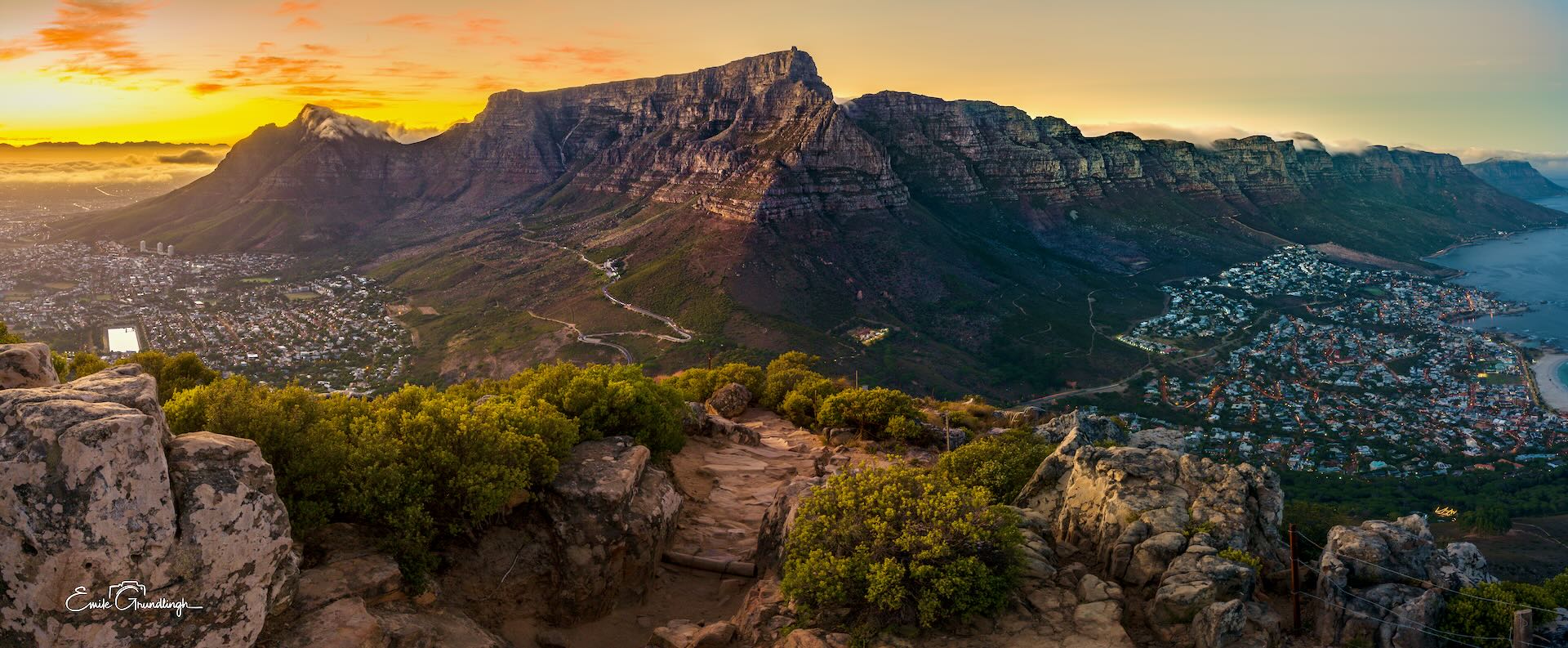Table Mountain and Twelve Apostles at golden sunrise from Lion's Head with Camps Bay below