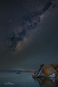 Milky Way arching over Millers Point granite boulders and calm False Bay waters at night