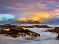 Table Mountain under golden storm clouds at sunset with wild waves at Bloubergstrand