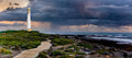 Storm Rolling In Kommetjie – dark storm clouds over Slangkop Lighthouse with boardwalk and fynbos