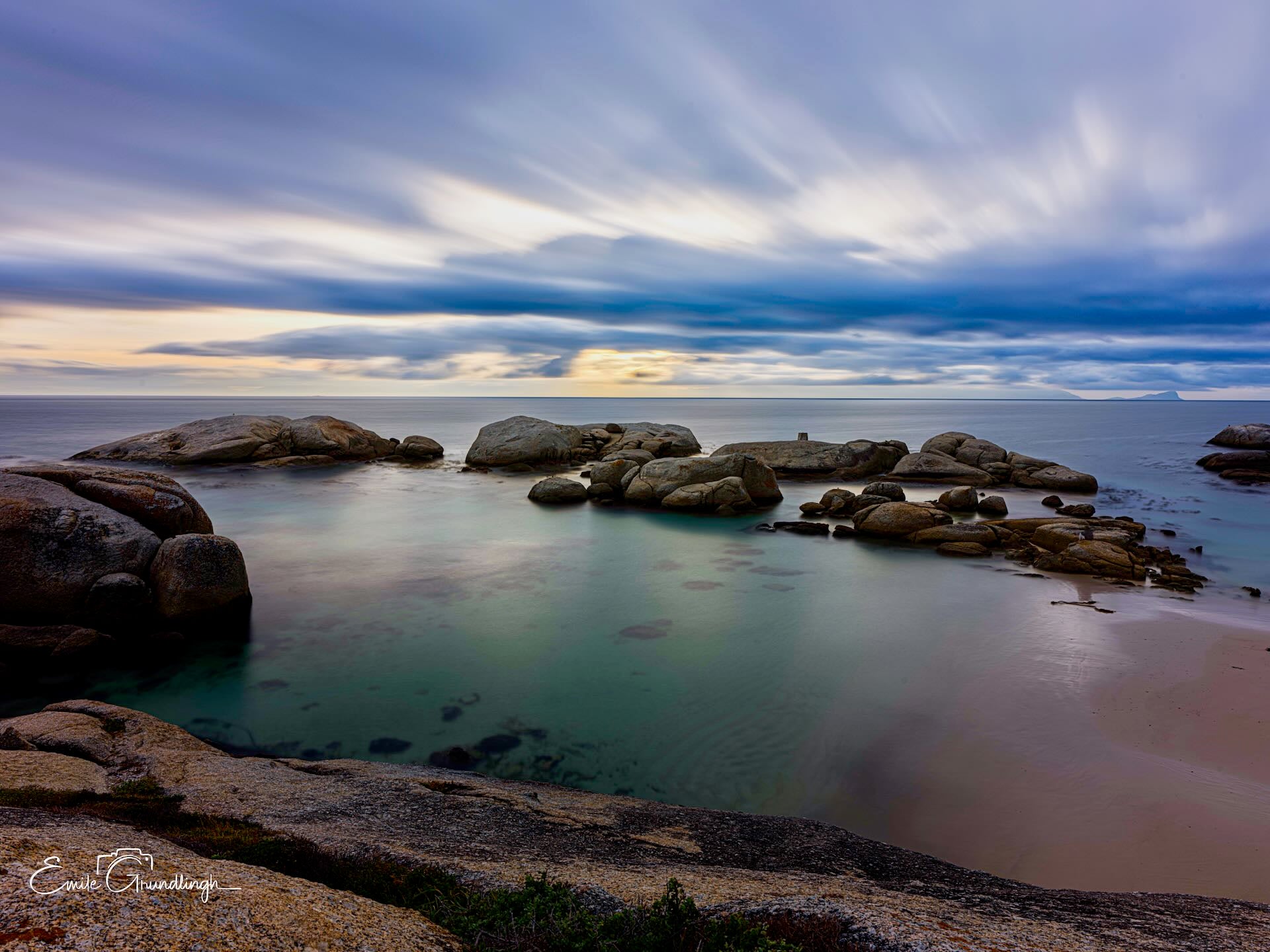 Windmill Beach at dusk with long exposure silky water, granite boulders and dramatic cloudy sky
