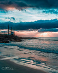 Metrorail train along the Glen Cairn coastline at sunset with dramatic storm clouds and golden sun rays over False Bay
