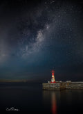Kalk Bay harbour lighthouse standing alone on harbour wall beneath the Milky Way at night