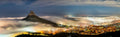 Lion's Head rising above a sea of mist over Cape Town at night wide panorama