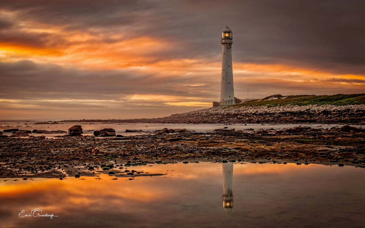 The Burning Hour Slangkop – Slangkop Lighthouse reflected in tidal pool under fiery orange sunset