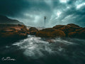 Between the Rocks Kommetjie – Slangkop Lighthouse framed by boulders under dramatic storm sky