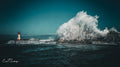 Colossal wave erupting high behind Kalk Bay harbour wall completely dwarfing the red lighthouse