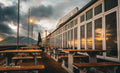Empty terrace of Dixies Restaurant and Bar at Kalk Bay harbour at sunset with Table Mountain silhouette and storm clouds