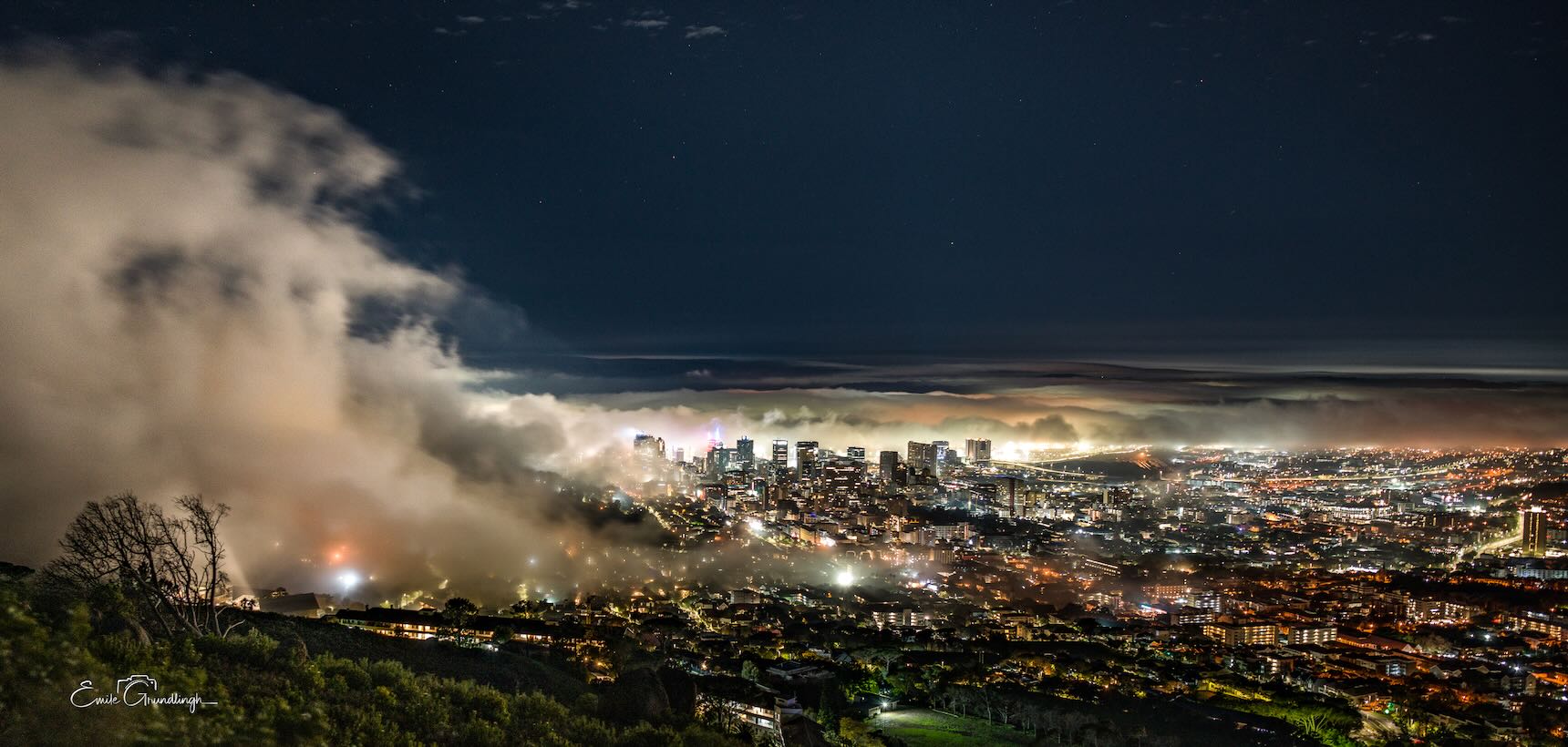 Cape Town city lights at night with a dramatic cloud wall rolling over the skyline