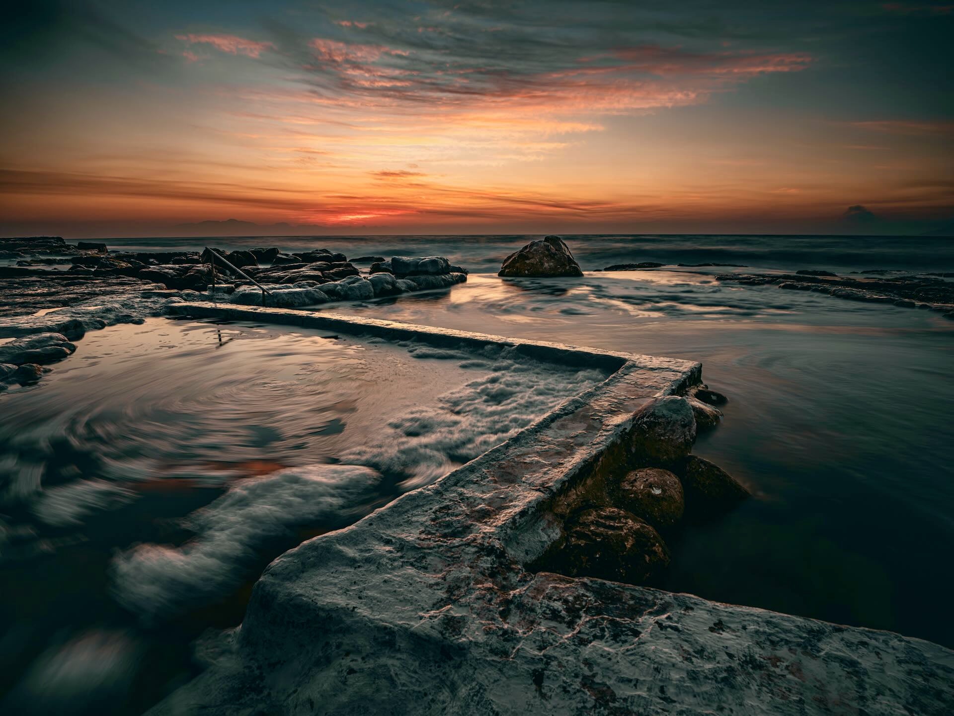 Wooleys Tidal Pool at sunset with silky water and fiery orange sky over False Bay