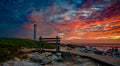 The Best Seat in the House – bench on Kommetjie boardwalk with blazing sunset and Slangkop Lighthouse