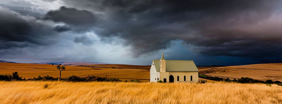 Award winning photography - white church in golden grasslands under dramatic storm clouds