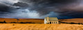 White chapel on golden plains under dramatic storm clouds