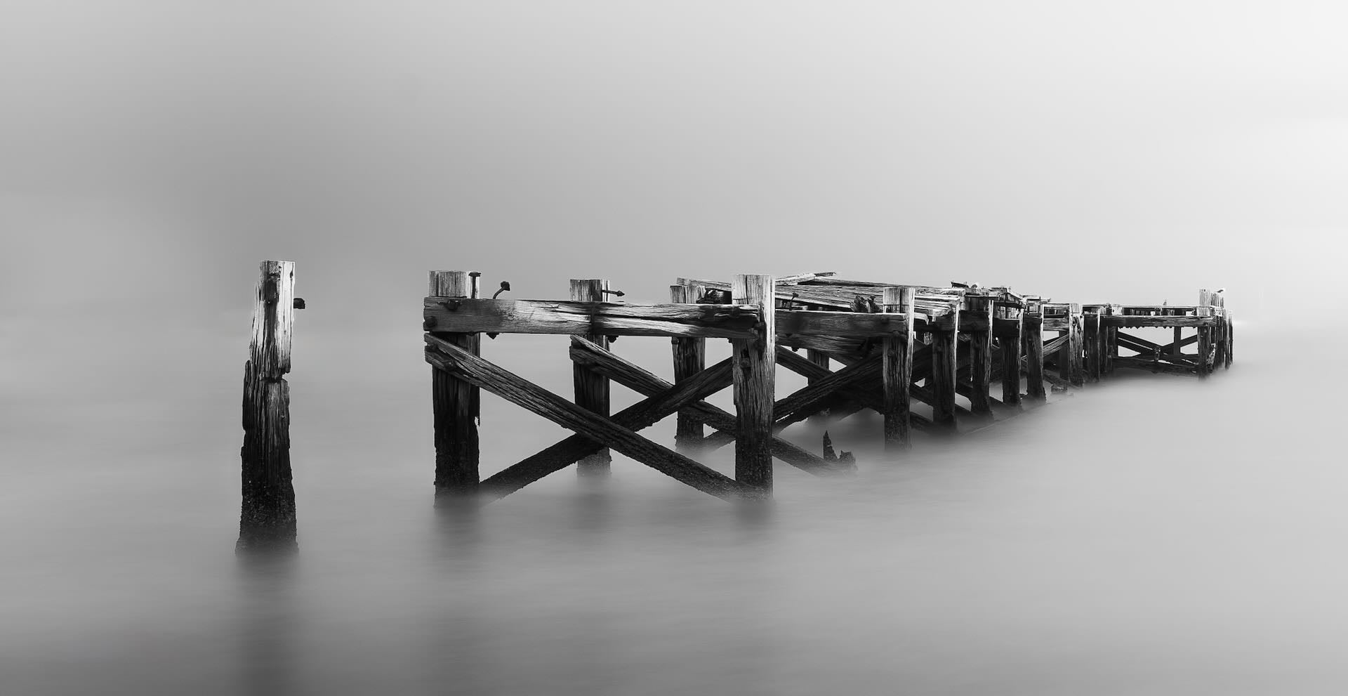 Ruins of the old Strand Jetty in silky misty water, black and white long exposure, False Bay