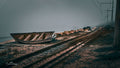 Wrecked wooden boat beside coastal railway tracks disappearing into thick sea mist at Makriels Beach, False Bay