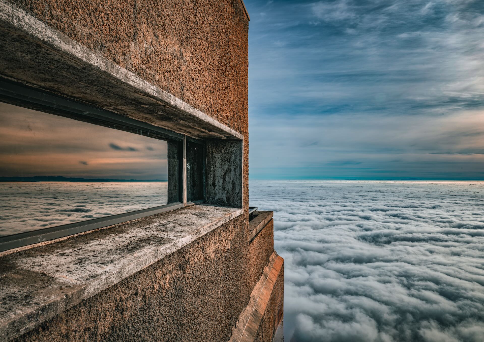 Table Mountain cable car station rising above an endless sea of clouds with window reflection