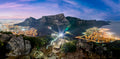 Table Mountain from Lion's Head at blue hour with hiker light trails and Cape Town city lights panorama