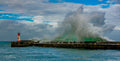 The Green Monster – massive emerald wave crashing over Kalk Bay harbour wall and lighthouse