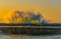 The Morning Runner – lone runner on Kalk Bay harbour wall with golden sunrise wave behind