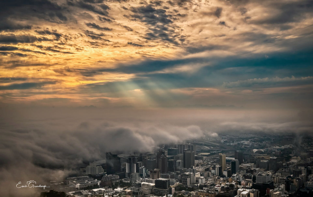 Cape Town CBD surrounded by low cloud beneath a dramatic golden sky, photographed by Emile Grundlingh.