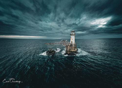 Aerial view of Roman Rock Lighthouse isolated in dark churning False Bay waters under dramatic swirling storm sky
