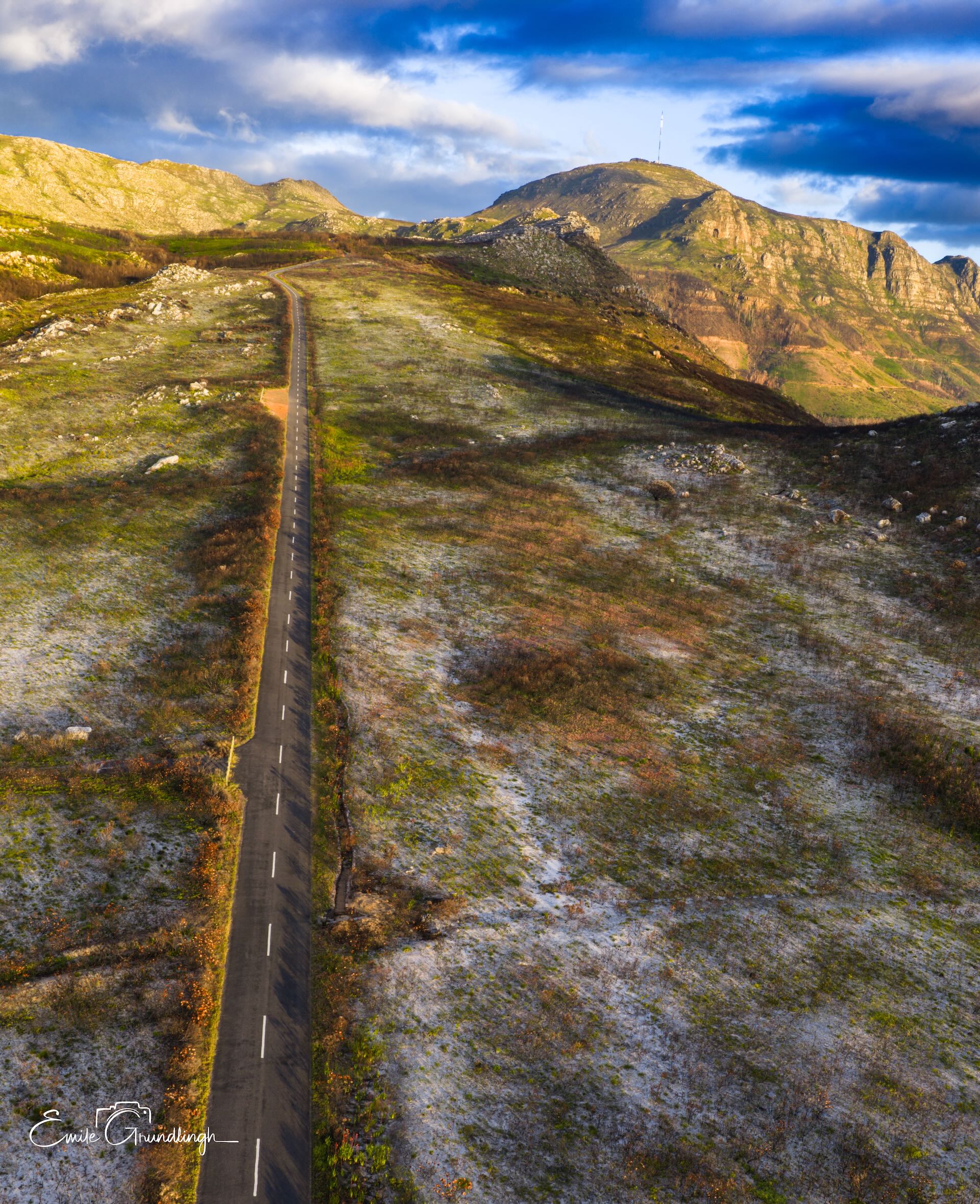 Aerial drone view of straight road through golden fynbos leading to Silvermine peaks Cape Peninsula
