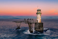 Roman Rock Lighthouse in soft pastel pink and lavender twilight with calm sea and cormorants on gantry, False Bay